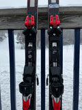 View of bindings of the Atomic 2023-2023 Redster G9 NASTAR level skis leaning against a railing